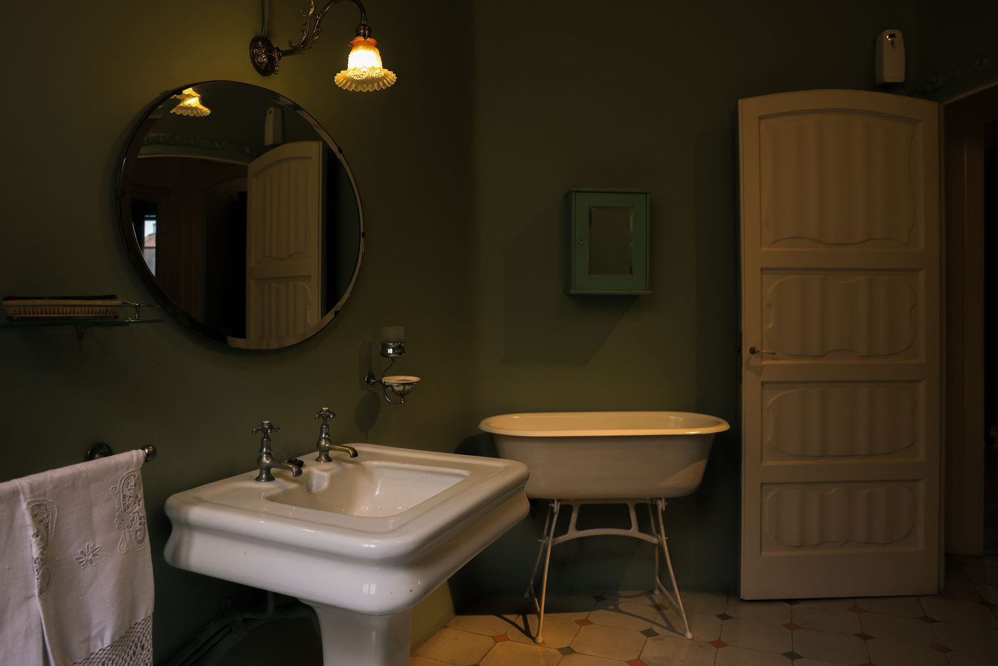 Traditional bathroom with a pedestal basin, roll-top bath and warm wall lights